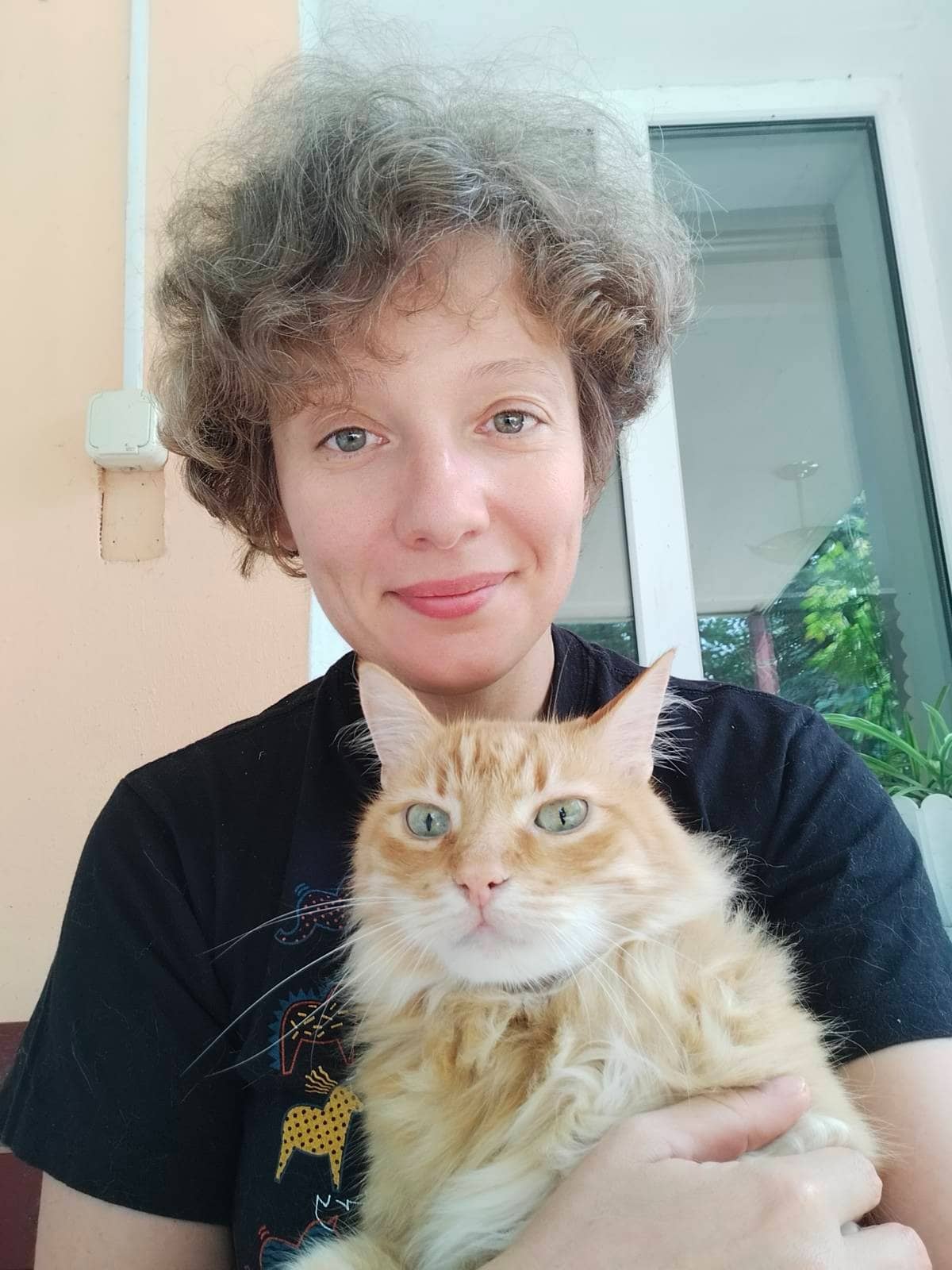 A woman holding a cat with curly hair.